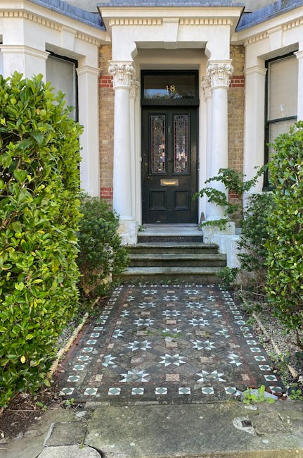 The image depicts the entrance to a period property featuring a classic black front door with decorative stained glass panels and a brass letterbox. Stone steps lead up to the door, flanked by white c